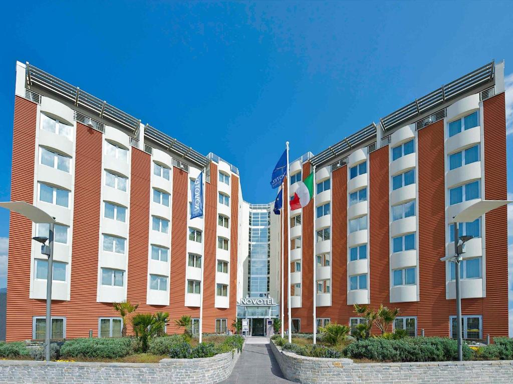 a hotel building with a flag in front of it at Novotel Salerno Est Arechi in Salerno