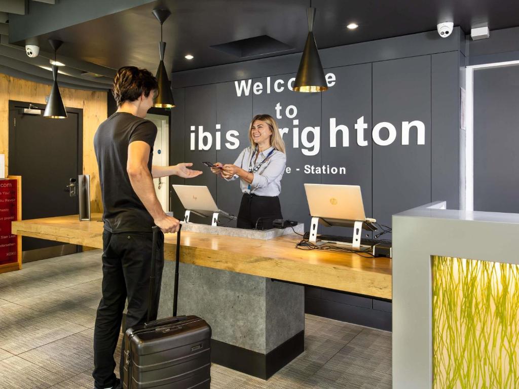 a man and a woman standing at a reception desk at ibis Brighton City Centre - Station in Brighton & Hove