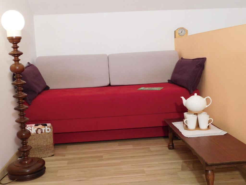 a bed in a room with a red bed with a table at Agroturystyka pod Czarną Sosną in Biały Ług