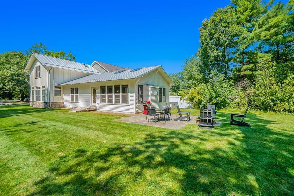 a white house with a patio and a yard at White Pines Cottage in Glen Arbor