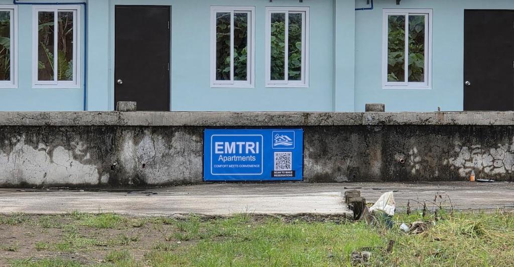 a blue exit sign in front of a house at Emtri Apartments in Sipak