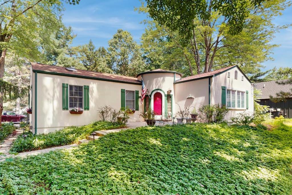a white house with a red door and a yard at Wine Down Cottage in Union Pier