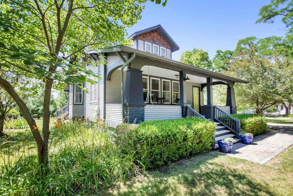 a white house with a porch and a tree at Three Oaks Retreat in Three Oaks