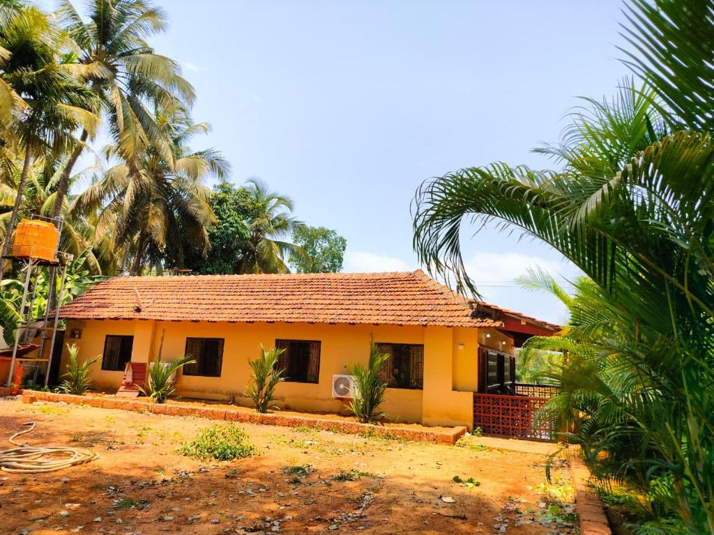 a yellow house with palm trees in front of it at Mangrove Village Inn in Kāsarkod