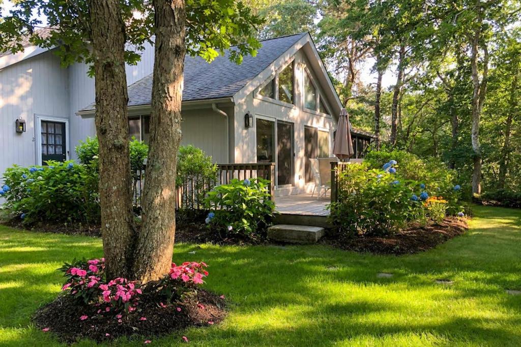 a house with a porch and a tree with flowers at Harbor Cove Cottage in Edgartown