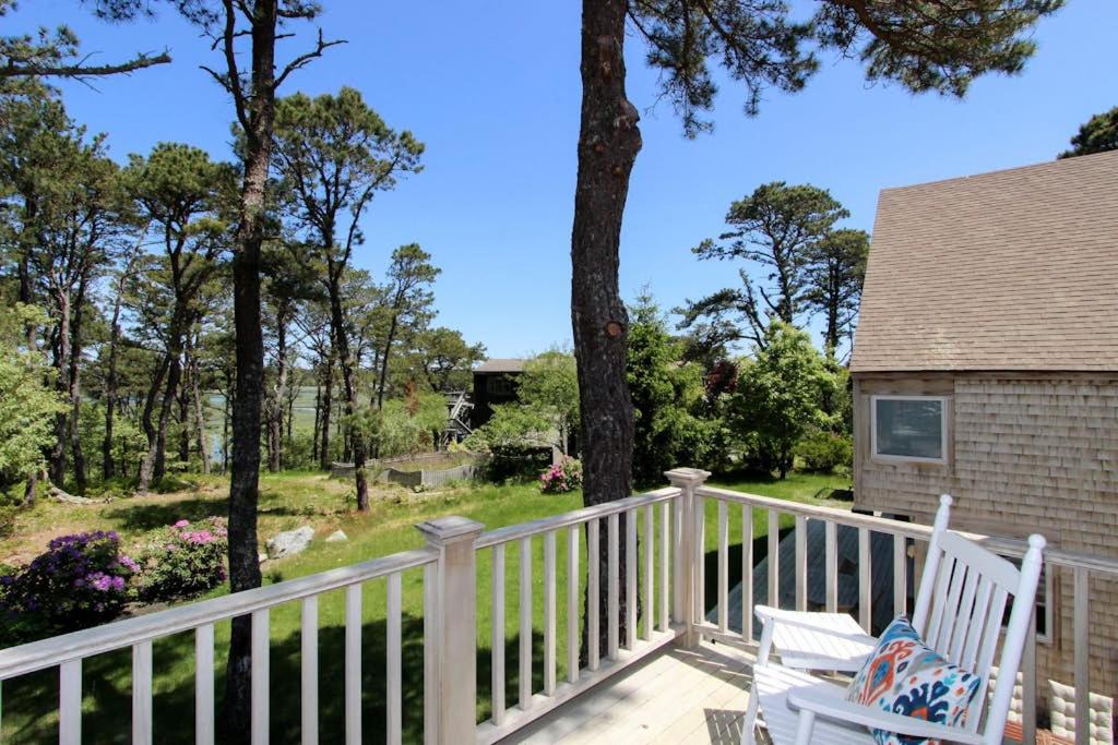 a porch with two white chairs and trees at Blackfish Bungalow in Wellfleet