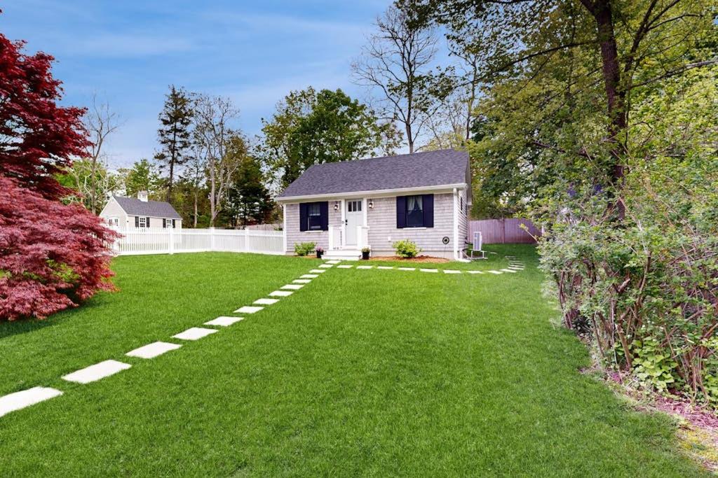 a yard with a white house and a white fence at The Quintessential Cape Cottage in Orleans