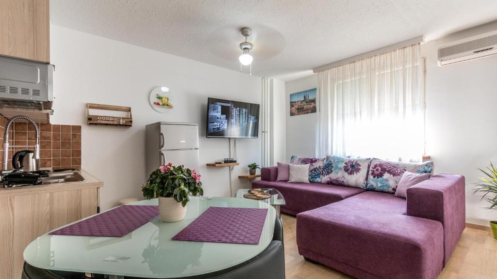 een woonkamer met een paarse bank en een tafel bij Lake Side Apartments by ZagrebRent in Zagreb