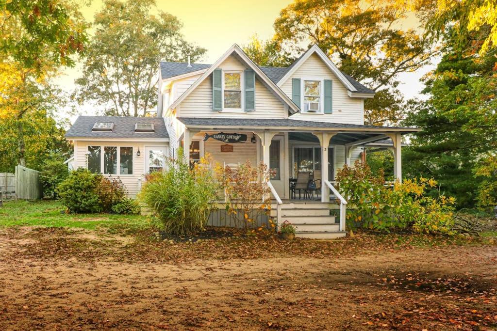 a white house with a porch and a yard at Canary Cottage in Oak Bluffs