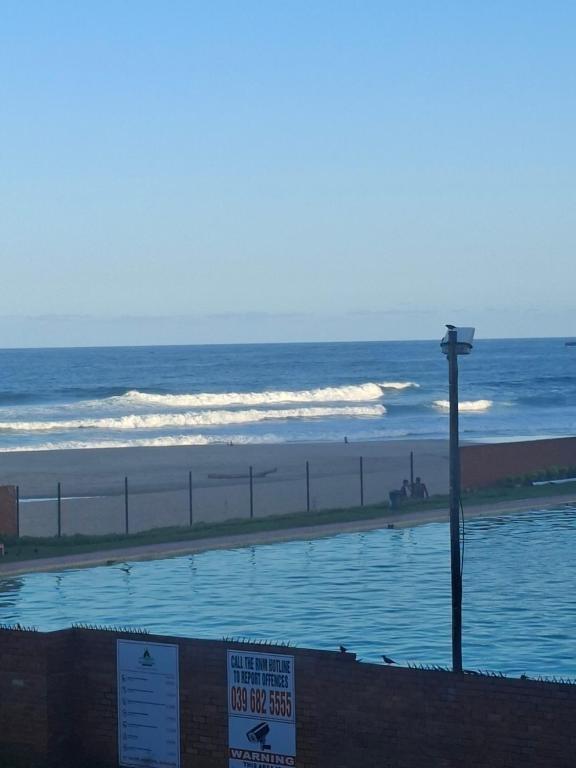 a swimming pool next to a beach with the ocean at Margate Boulevard - Seaview Apartment in Margate