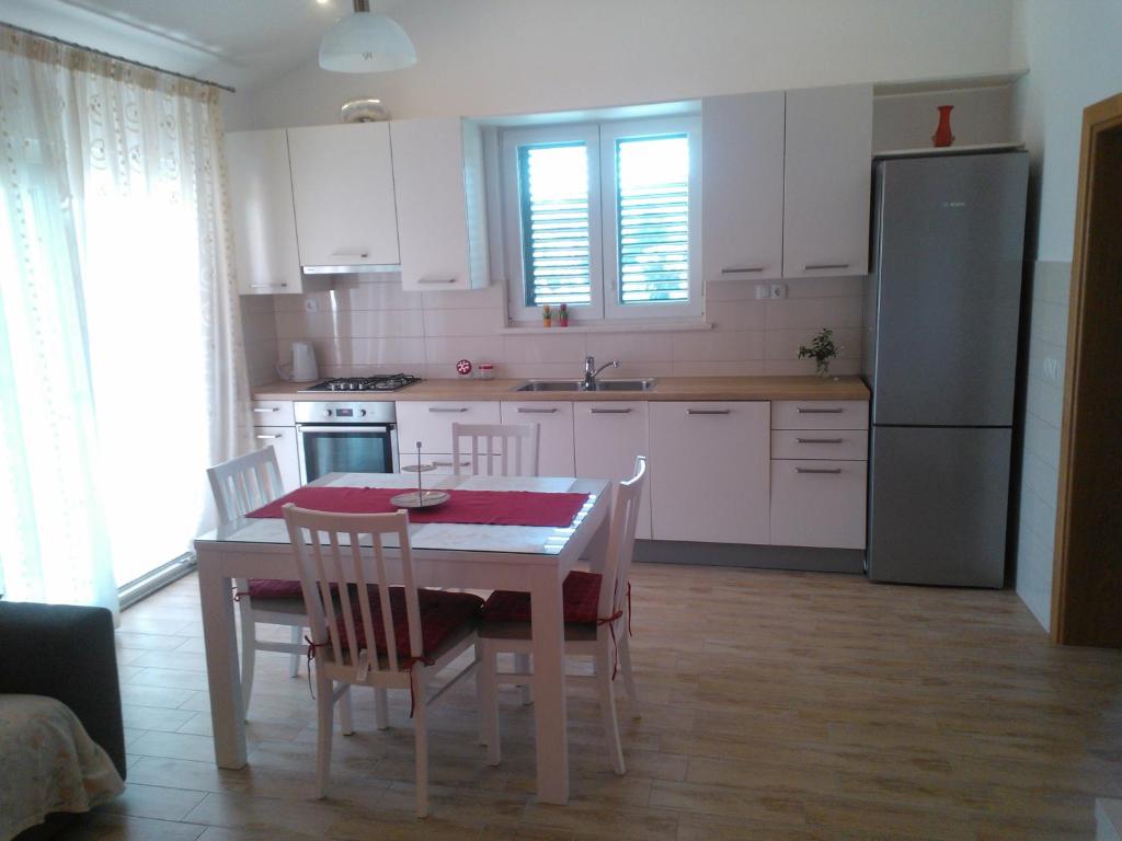 eine Küche mit einem Tisch mit Stühlen und einem Kühlschrank in der Unterkunft Tone & Marta Apartments in Rogoznica