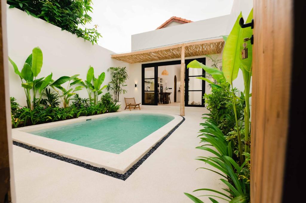 an outdoor swimming pool in a house with plants at Rumah Mana Villa in Tabanan