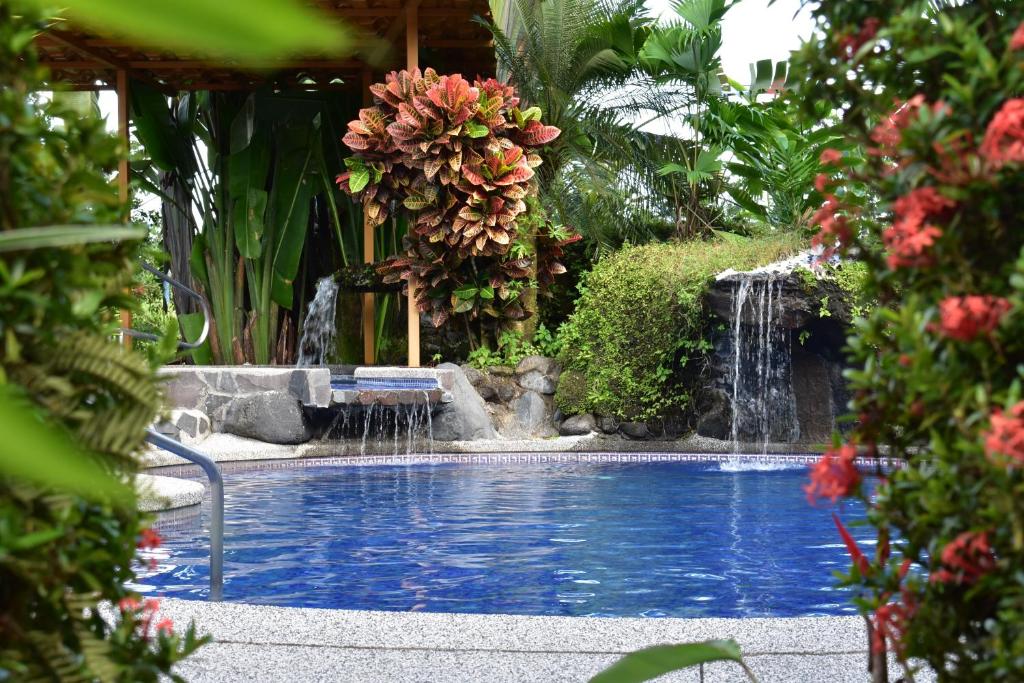 a swimming pool with a waterfall in a garden at Hotel Roca Negra Del Arenal in Fortuna