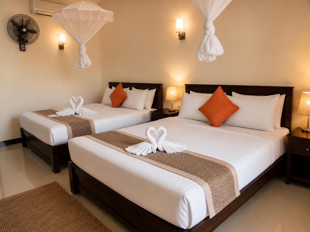 two beds in a hotel room with white and orange pillows at Rainbow Safari & Lodge in Udawalawe