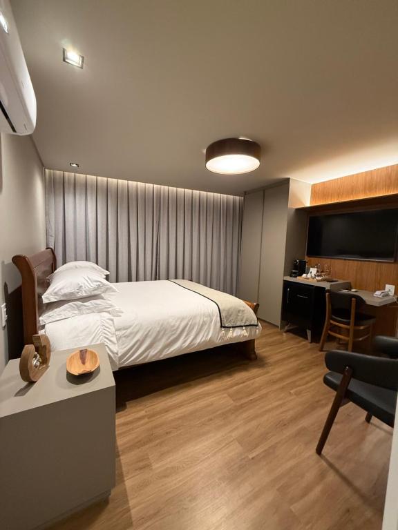 a hotel room with a bed and a desk and a room at Suíte Boutique 302 Cheia de Graça in Divinópolis