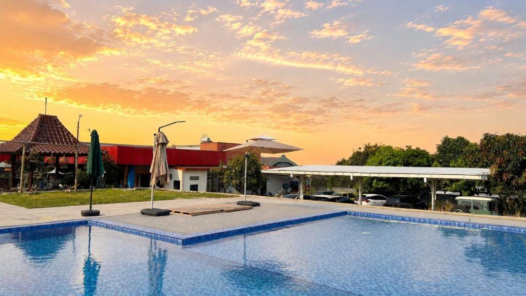 a swimming pool with a sunset in the background at Oak Lawang in Lawang