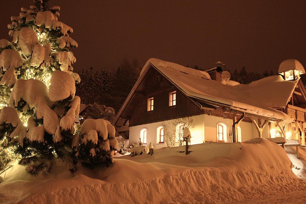 B&B Na kopečku في روكيتنسي ناد جيزيرو: منزل مغطى بالثلج ليلا مع شجرة عيد الميلاد