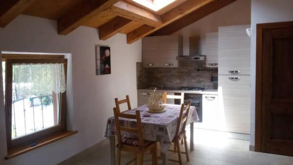 cocina con mesa y sillas y cocina con ventana en Mansarda Monte Bianco, en La Salle