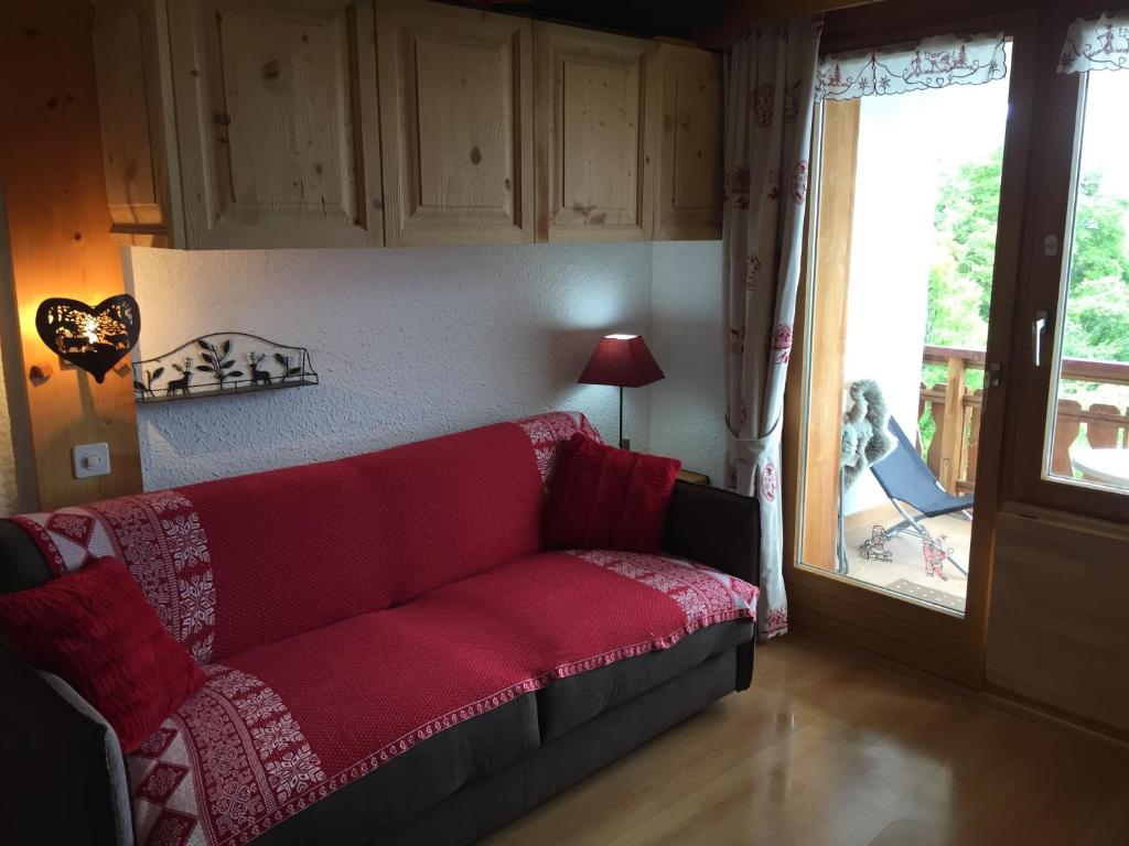 a living room with a red couch in front of a door at Le Bristol - Villars Bristol Apartments in Villars-sur-Ollon