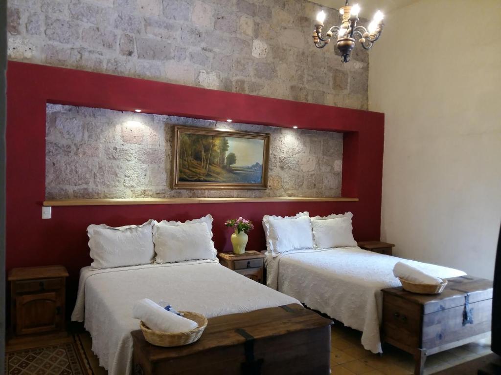 a bedroom with two beds and a red wall at Casa Limonchelo Hotel B&B in Morelia