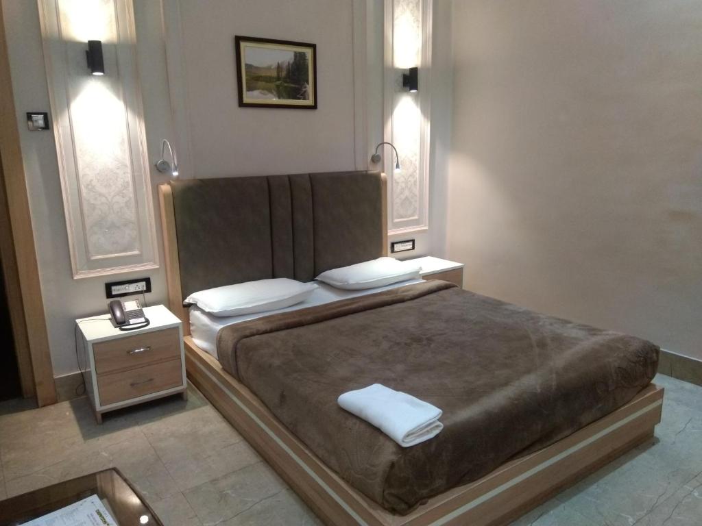 a bedroom with a large bed and two night stands at The Boulevard Hotel in Jamshedpur