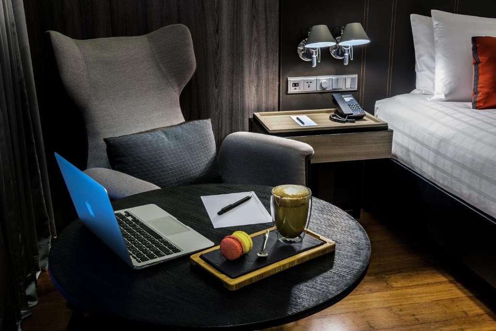 A compact in-room work setup beside the bed, with a laptop table and lounge chair.
