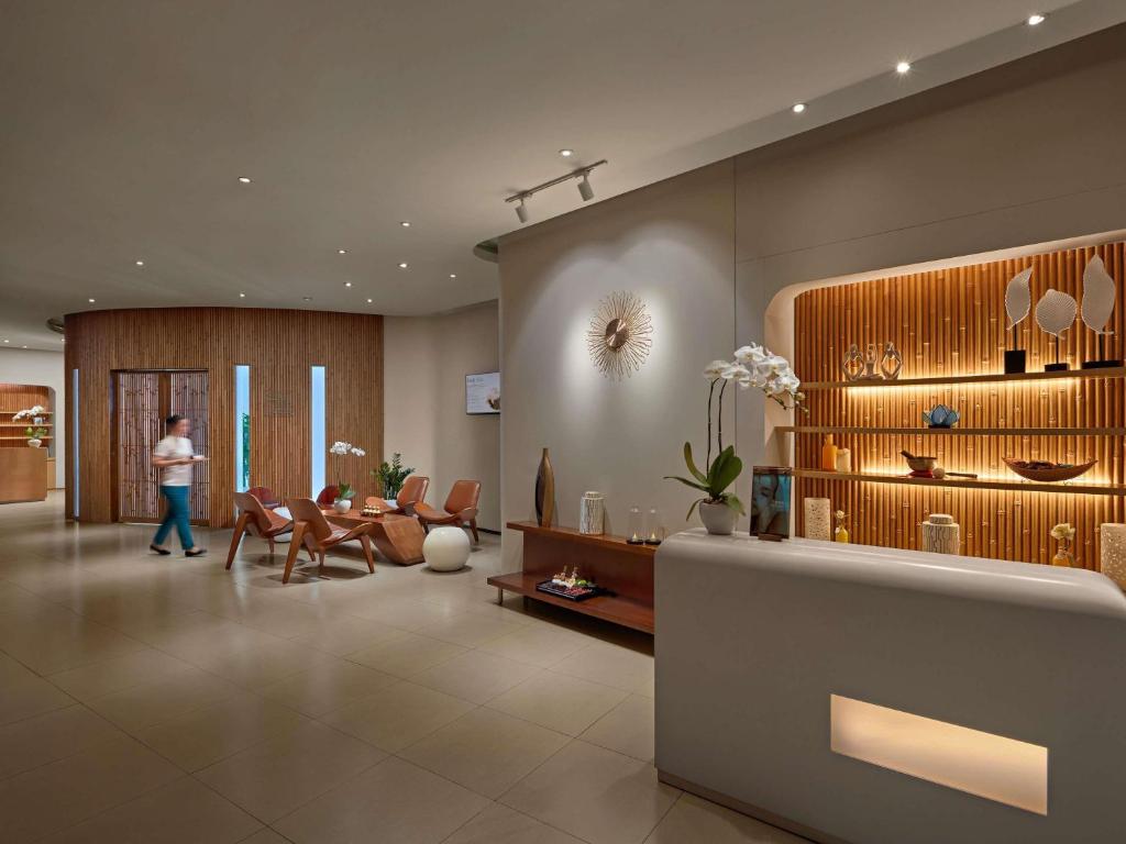 A contemporary reception lounge combines a long desk, display shelving, and casual seating.