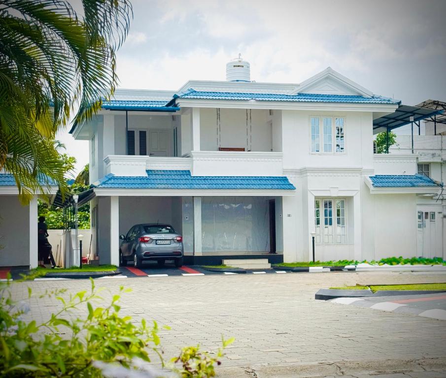 a white house with a car parked in front of it at Zenaura Casa Villa 2 in Cochin