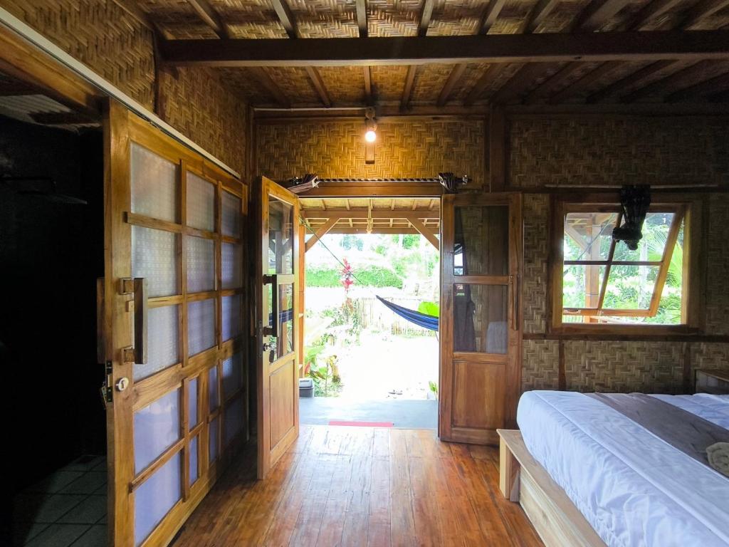 a bedroom with a bed and an open door at Tetebatu Sasak House Bungalow in Tetebatu