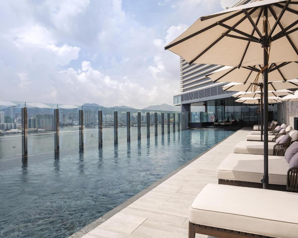 a pool with chairs and umbrellas next to the water at Hyatt Centric Victoria Harbour in Hong Kong