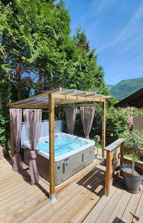 a hot tub under a gazebo on a deck at chalet cosy, jacuzzi privé, calme, idéal moto rando vélo in Bellecombe