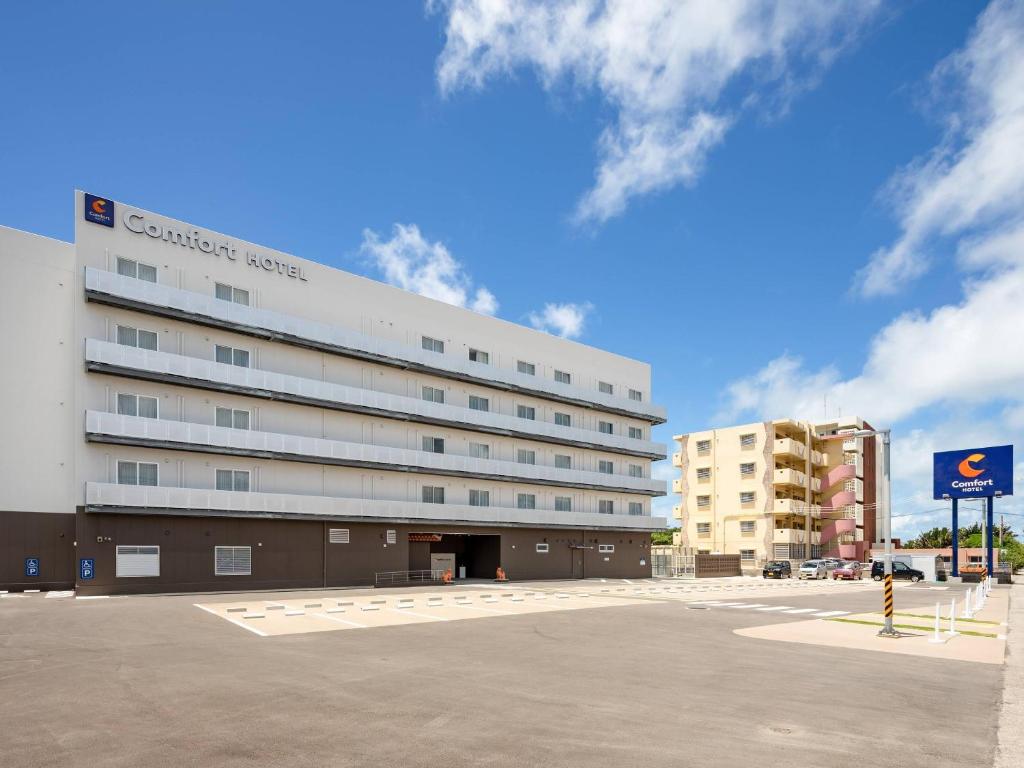 a large white building in front of a parking lot at Comfort Hotel ERA Ishigaki Island in Ishigaki Island
