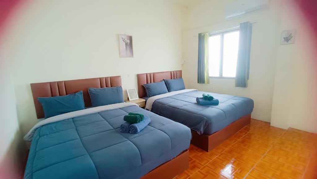 two beds with blue pillows in a bedroom at Pai Town Home in Pai