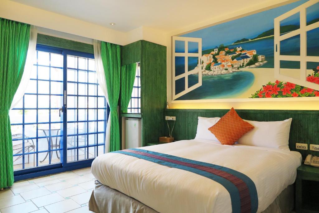 a bedroom with a large bed with a painting on the wall at Kenting Sin Sin Hotel II in Kenting