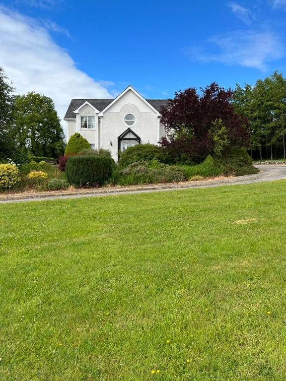 a white house with a green lawn in front of it at White House tree view in Drumshanbo