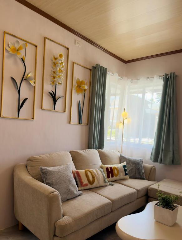 a living room with a couch and flowers on the wall at Skys Transient House Unit 1 in Manolo Fortich