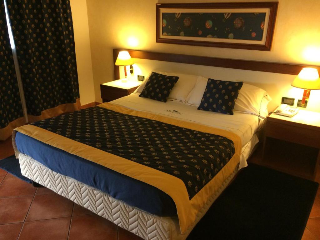 Villanova MonferratoにあるArcotelの大型ベッド1台、テーブル2台が備わるホテルルームです。