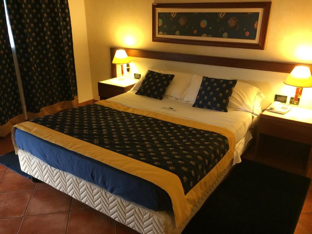 a hotel room with a large bed with two tables at Arcotel in Villanova Monferrato