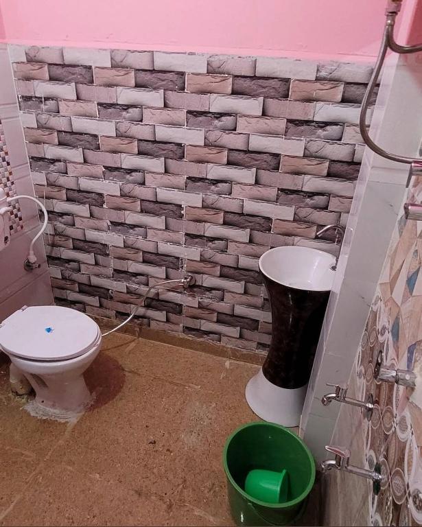 a bathroom with a toilet and a brick wall at Hotel blue moon in Shāmli