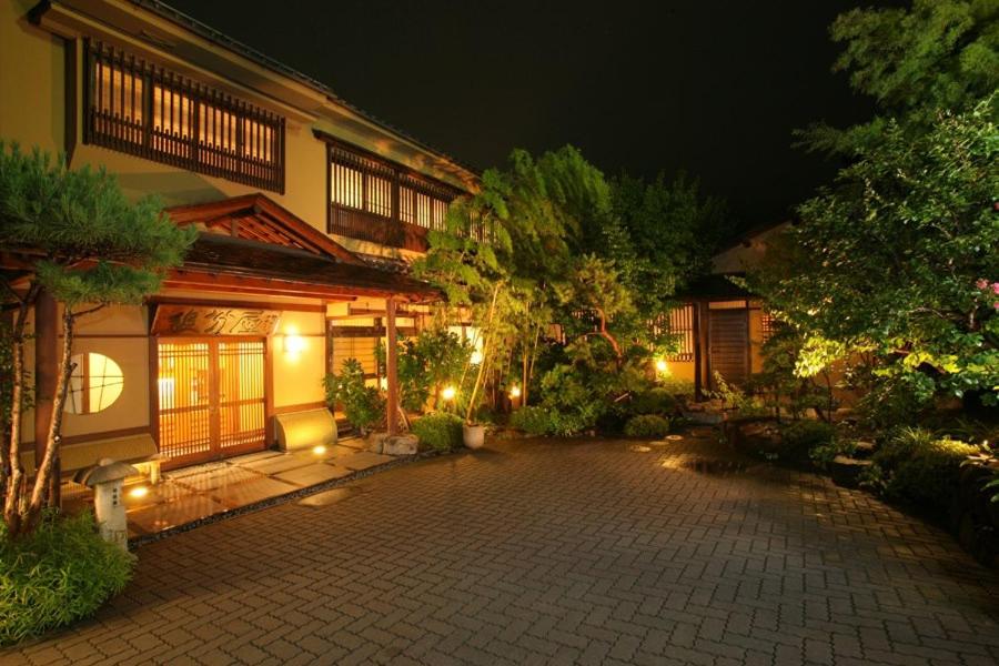 un patio de una casa por la noche con luces en Oiwakeya Ryokan, en Matsumoto