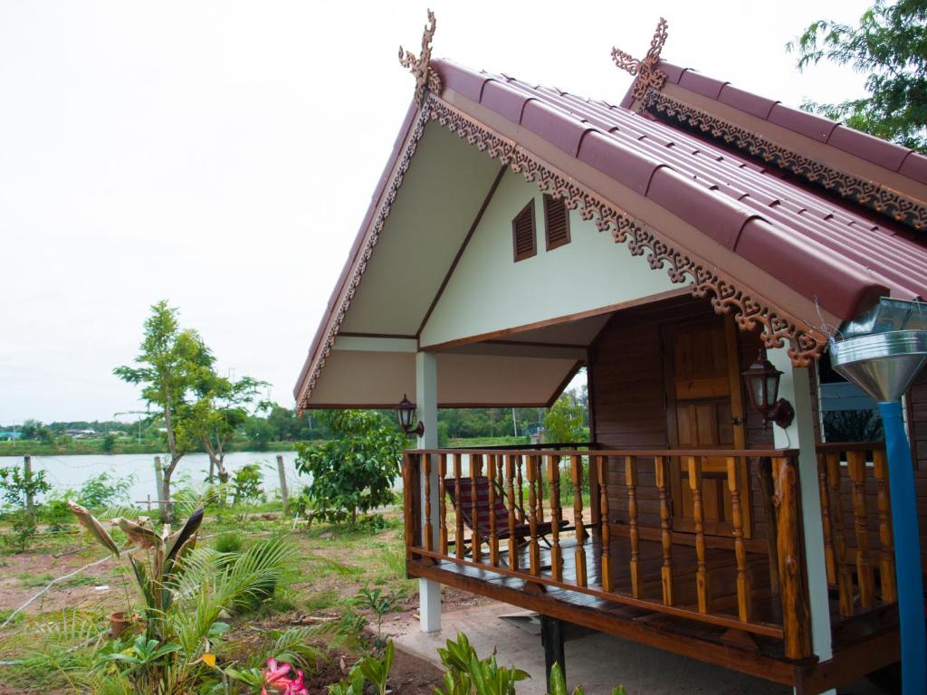 een klein huis met een balkon naast een waterlichaam bij Jamsai Resort in Phu Khieo