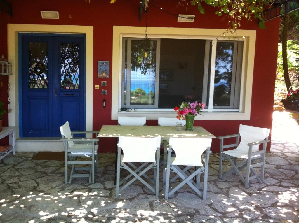 レフカダにあるVolpetta Houseの青いドア付きの家の前のテーブルと椅子