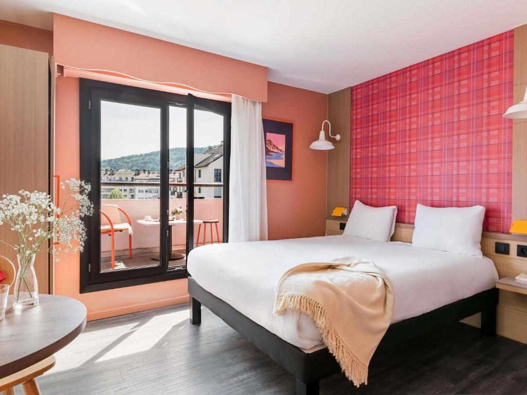 a bedroom with a large bed and a large window at ibis Styles Annecy Centre Gare in Annecy