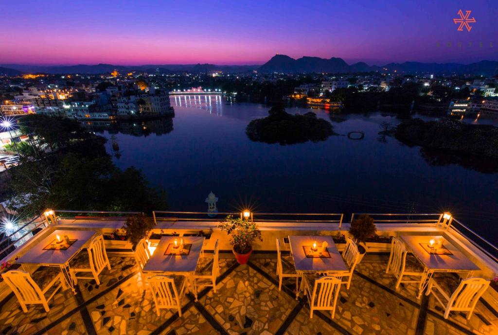 a view of a lake at night with tables and chairs at Zostel Udaipur in Udaipur