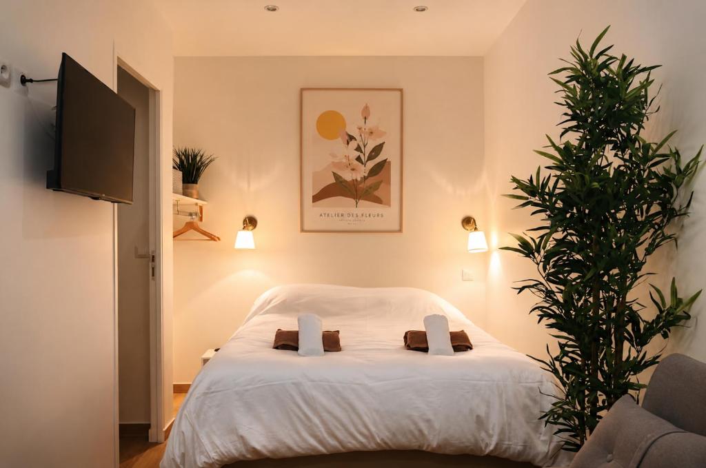 a bedroom with a white bed with a plant at Les Escales de Choisy in Choisy-le-Roi