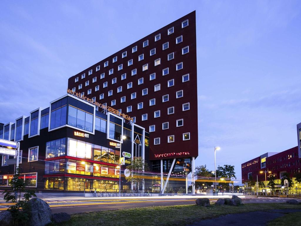 a tall building in a city at night at Mercure Hotel Amersfoort Centre in Amersfoort