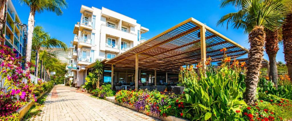 a building with a canopy over a garden with flowers at Hotel Royal in Vlorë