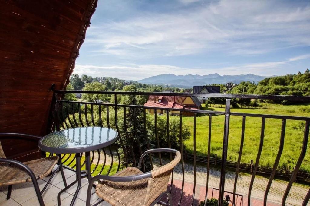 a balcony with a table and chairs and a view at Willa za Wodą in Zakopane