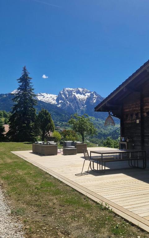 a patio with a picnic table and mountains in the background at Chalet de Manigod in Manigod