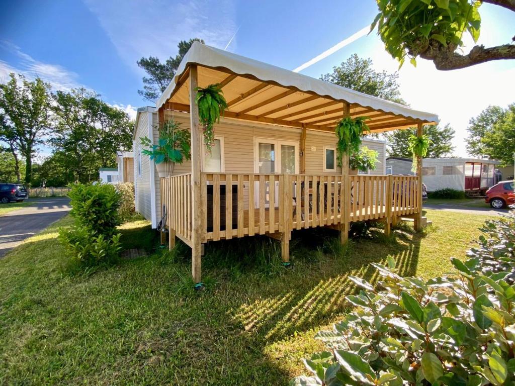 a tiny house with a porch with a roof at MOBIL-HOME "B30" tout confort avec piscine & lave-linge gratuit in Mimizan